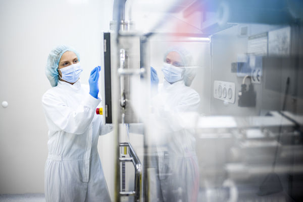 Une personne travaille en tenue de protection dans l'industrie pharmaceutique