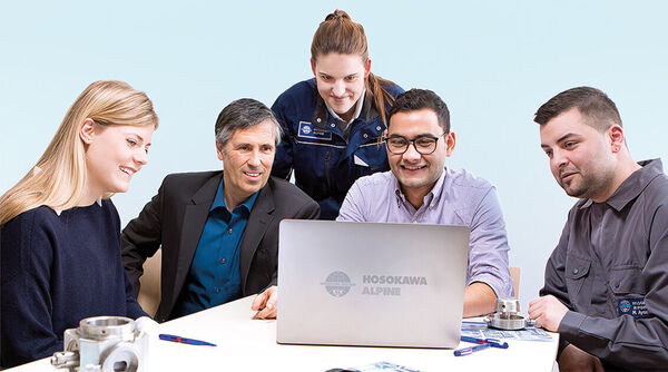 Ein Team von Mitarbeitern bei Hosokawa Alpine sitzt um einen Laptop