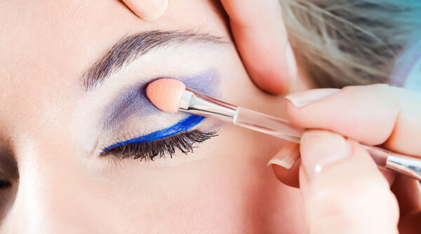 Visage maquillé avec du fard à paupières bleu au niveau des yeux.