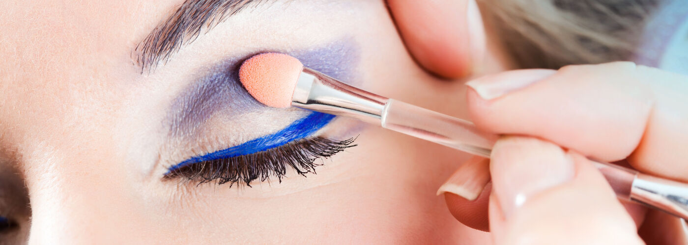 Visage maquillé avec du fard à paupières bleu au niveau des yeux.